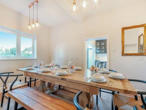 A dining area with a wooden table set for six, surrounded by chairs.