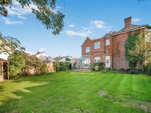 A residential property with a well-maintained lawn, a brick house with a conservatory, and a garden area. - The Old Doctors Manor House (Whitstable)