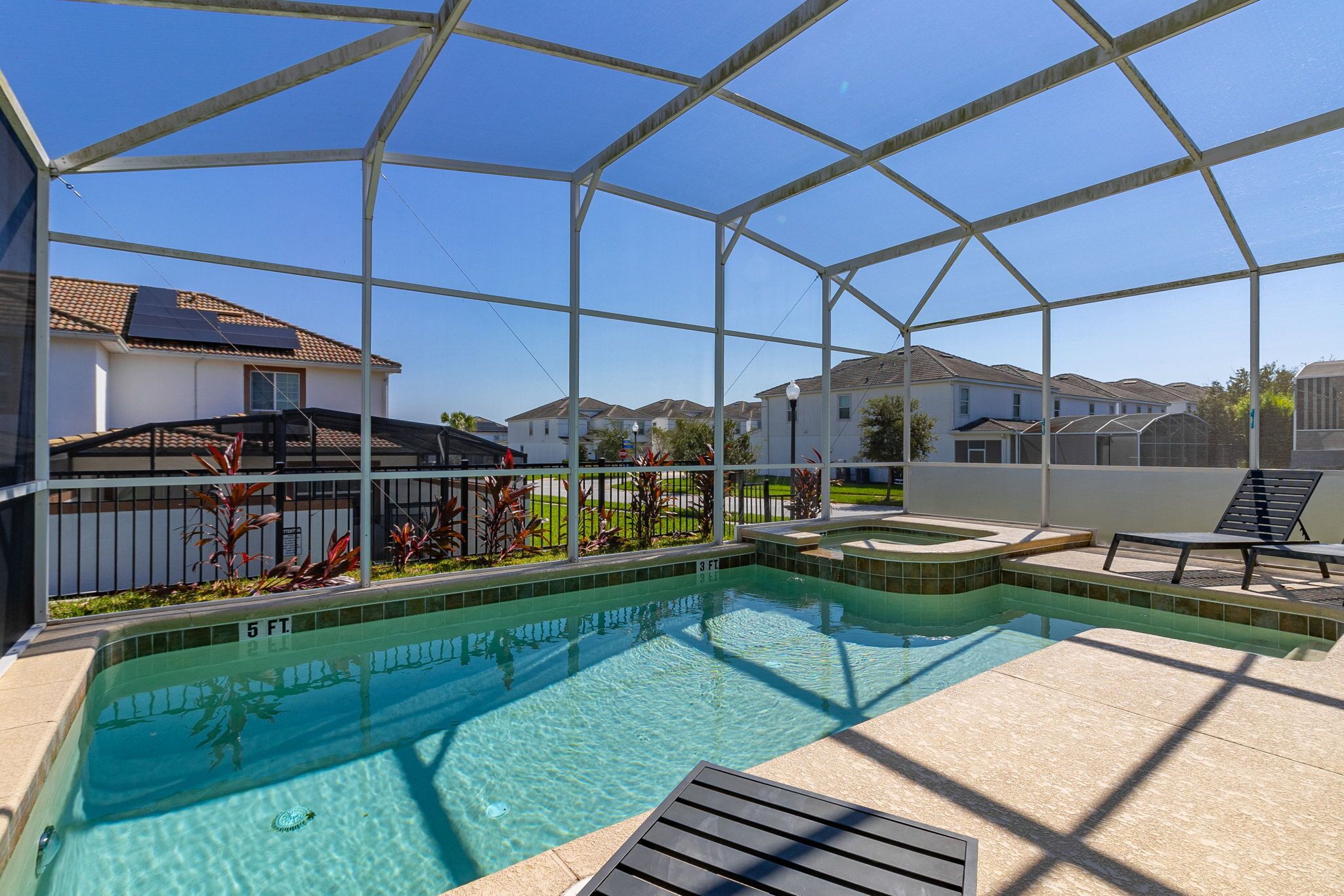 Une piscine couverte à l’eau d’un bleu limpide, entourée d’une structure en métal, et une terrasse carrelée avec des chaises longues.
