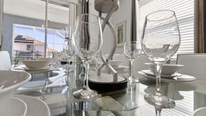 A modern dining area with a glass table, clear glassware, and a minimalist design. - Luxury 6BR Escape – Pool, Water Slides & Lazy River Near Disney! (Four Corners)