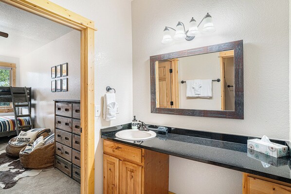 A bathroom with a wooden cabinet, a sink, and a mirror.