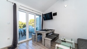 Uma sala de estar moderna com mesa de centro de vidro, televisão de tela plana na parede e porta de correr de vidro que dá para uma área externa.