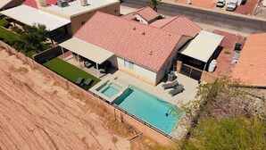 An aerial view of a residential property with a swimming pool, a covered patio, and a detached garage.