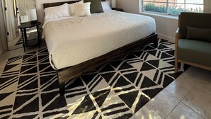 A bedroom with a bed, a ceiling fan, a window, a chair, and a rug.