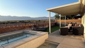 A rooftop patio with a swimming pool, outdoor furniture, and a view of mountains.