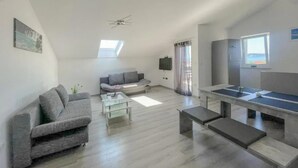 A modern living room with a grey sofa, a coffee table, and a ping pong table.