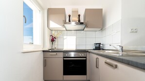 A modern kitchen with a built-in oven, a stainless steel range, and a window providing natural light.