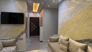 A modern living room with a sofa, a coffee table, and a flat-screen TV. - Modern, elegant and comfortable apartment in Marrakech (Marrakech)