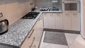 A modern kitchen with white cabinets, a granite countertop, a built-in oven, and a gas stove. - Modern, elegant and comfortable apartment in Marrakech (Marrakech)