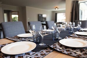 A dining table set with plates, glasses, and cutlery, with a patterned table runner.