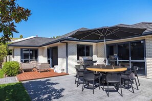 A modern house with a patio, outdoor seating, and a barbecue area.