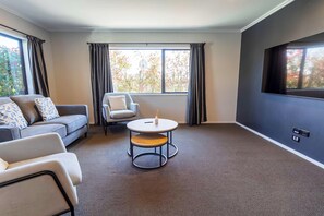 A modern living room with a sofa, armchair, and round table.