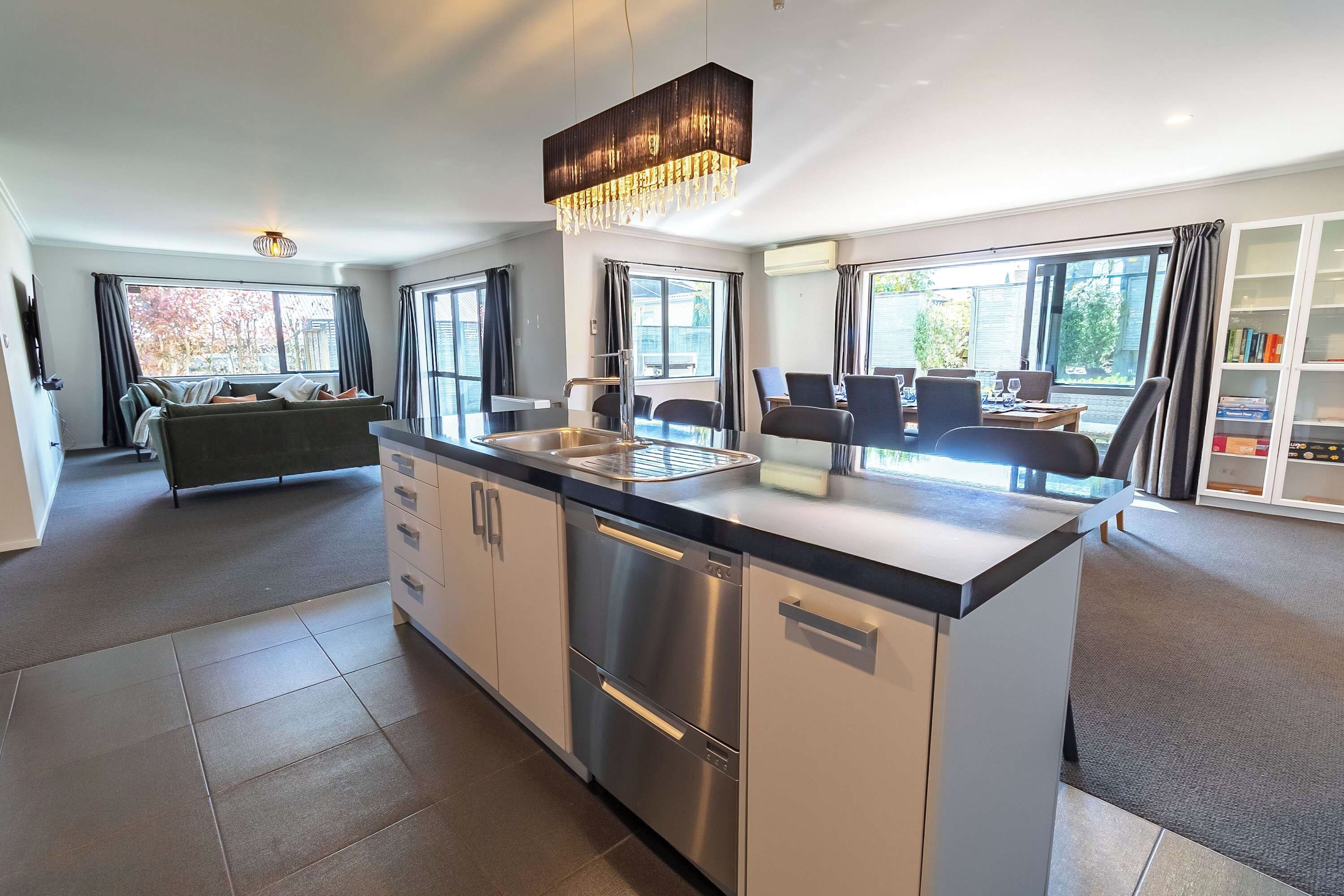 A modern kitchen with a central island, stainless steel appliances, and a dining area with chairs and a table.
