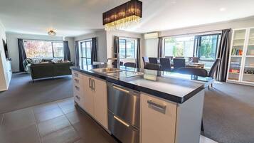 A modern kitchen with a central island, stainless steel appliances, and a dining area with chairs and a table.