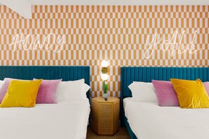 Ein Hotelzimmer mit zwei Betten, einer karierten Wand und Neonreklamen.
