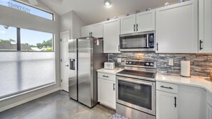 A modern kitchen with white cabinets, stainless steel appliances, a microwave, and a large window overlooking a body of water. - 3-bed house in fabulous Fort Myers with WiFi, AC,   6 miles from the Airport.   (Fort Myers)