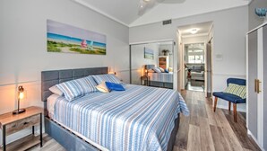 A bedroom with a bed, nightstands, a ceiling fan, a painting, and a hallway leading to a bathroom. - 3-bed house in fabulous Fort Myers with WiFi, AC,   6 miles from the Airport.   (Fort Myers)