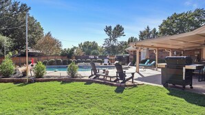 A backyard with a swimming pool, patio furniture, and a covered barbecue area. - Resort Pool & Spa Retreat with Game Room, Patio, Foosball & BBQ (North Richland Hills)