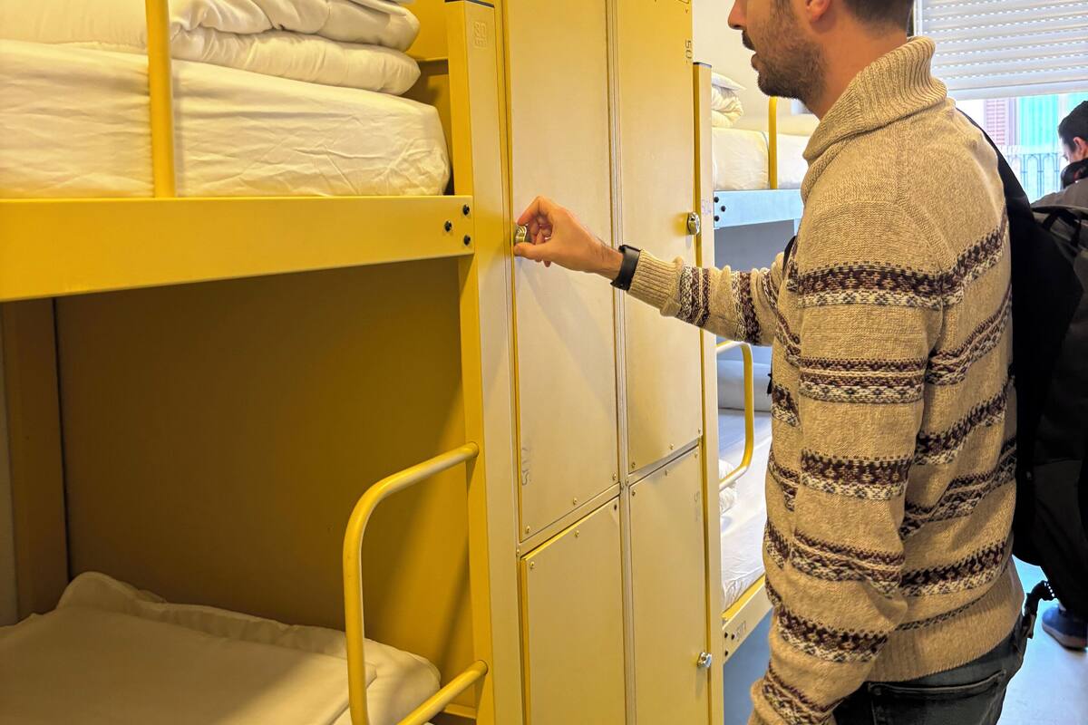 Iemand opent een geel stapelbed met witte beddengoed.