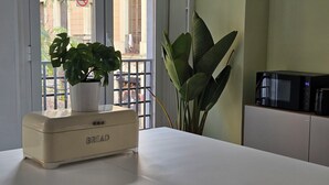 A kitchen with a bread maker, a potted plant, and a microwave. - Hey Lola Hostel (Barcelona)