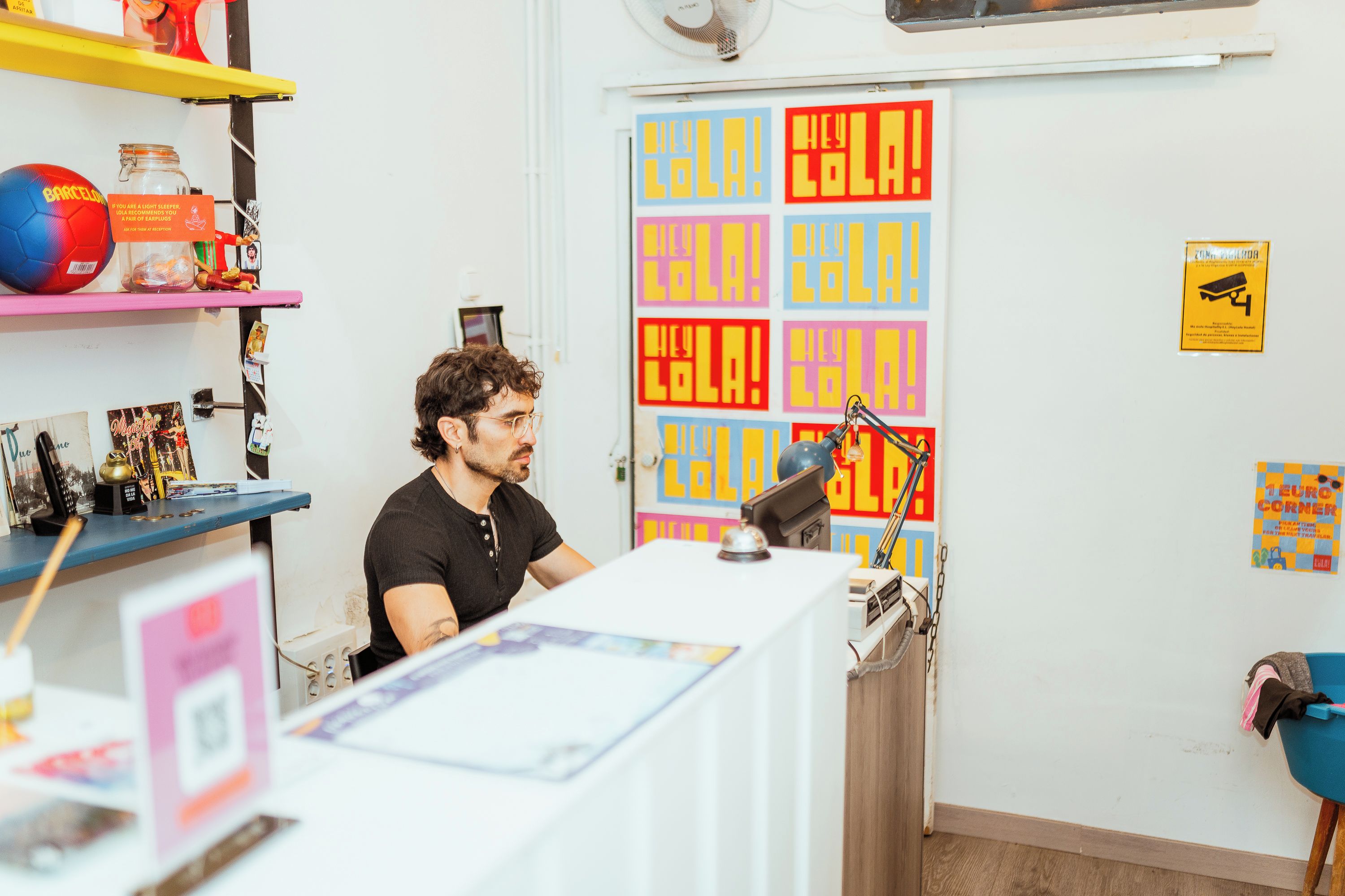 A room with a desk, shelves with various items, and colorful posters on the wall.