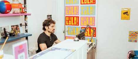 A room with a desk, shelves with various items, and colorful posters on the wall.