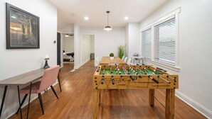 Una habitación con mesa de fútbol, mesa de comedor y una silla.