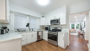Una cocina moderna con armarios blancos, electrodomésticos de acero inoxidable y suelo de madera.