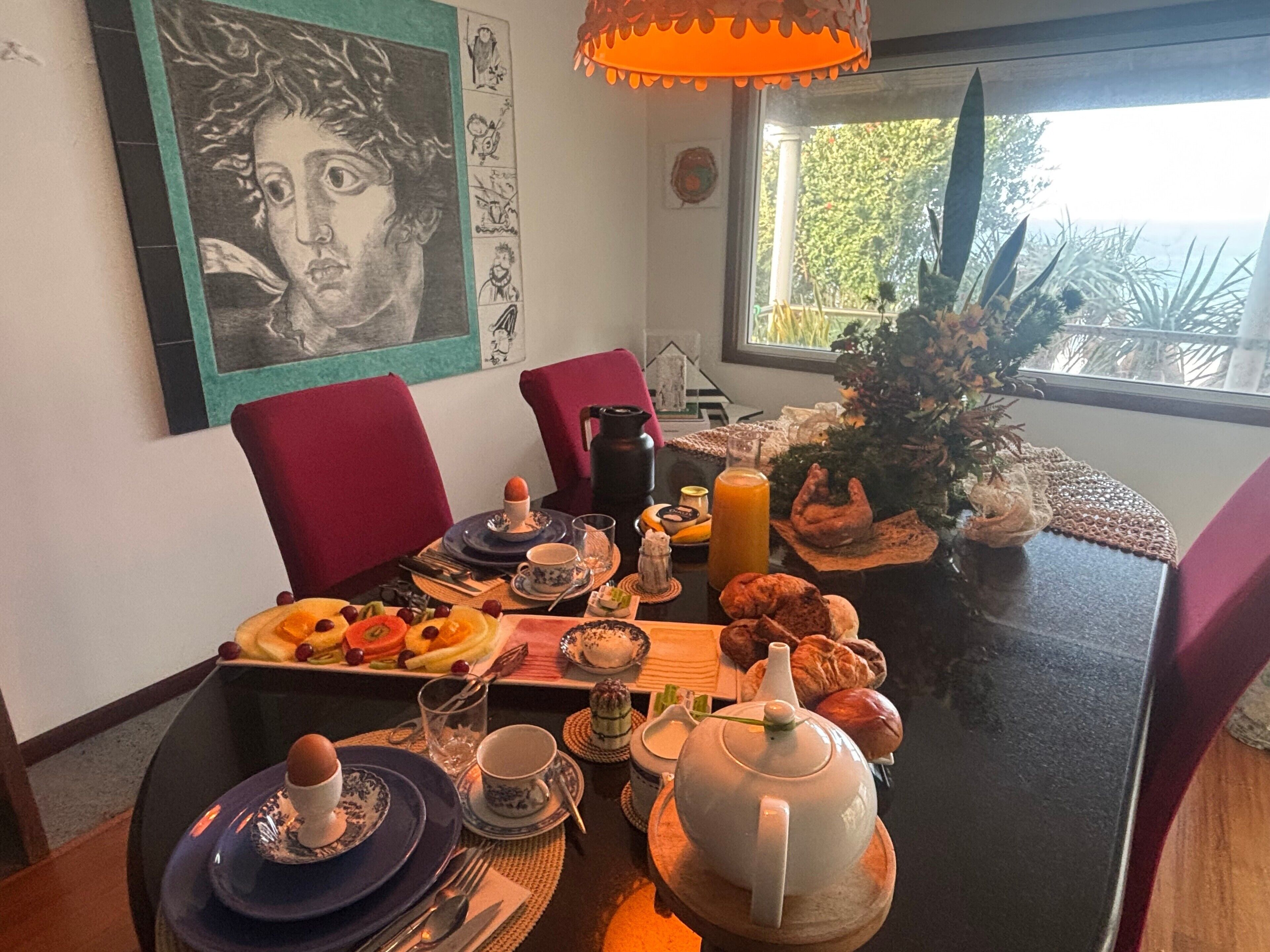 Et spisebord dækket med tallerkener, kopper, et te-stel og et juletræ.