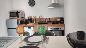 A modern kitchen with a microwave, coffee maker, and a clock on the wall.