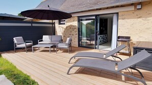 A deck with lounge chairs, a table, and an umbrella.