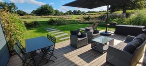 Een terras buiten met een tafel, stoelen en een bank.