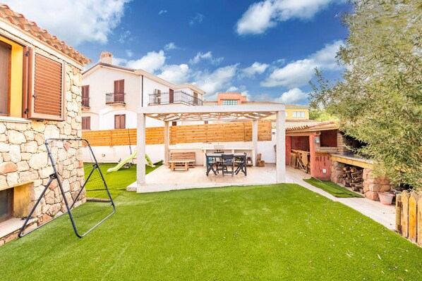 Eine Terrasse mit Tisch und Stühlen, eine Steinmauer und eine Pergola.
