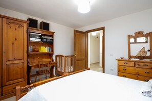 Ein Schlafzimmer mit einem hölzernen Bett, einem Schrank, einem Schreibtisch und einer Kommode.