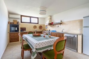 A compact kitchen with a dining table, chairs, a dishwasher, and a window.