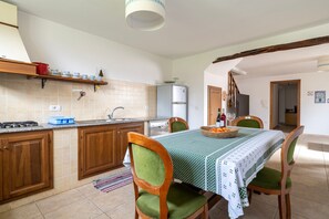 Eine Küche mit Essbereich, Holzschränken, einem Kühlschrank und einem Tisch mit Stühlen.