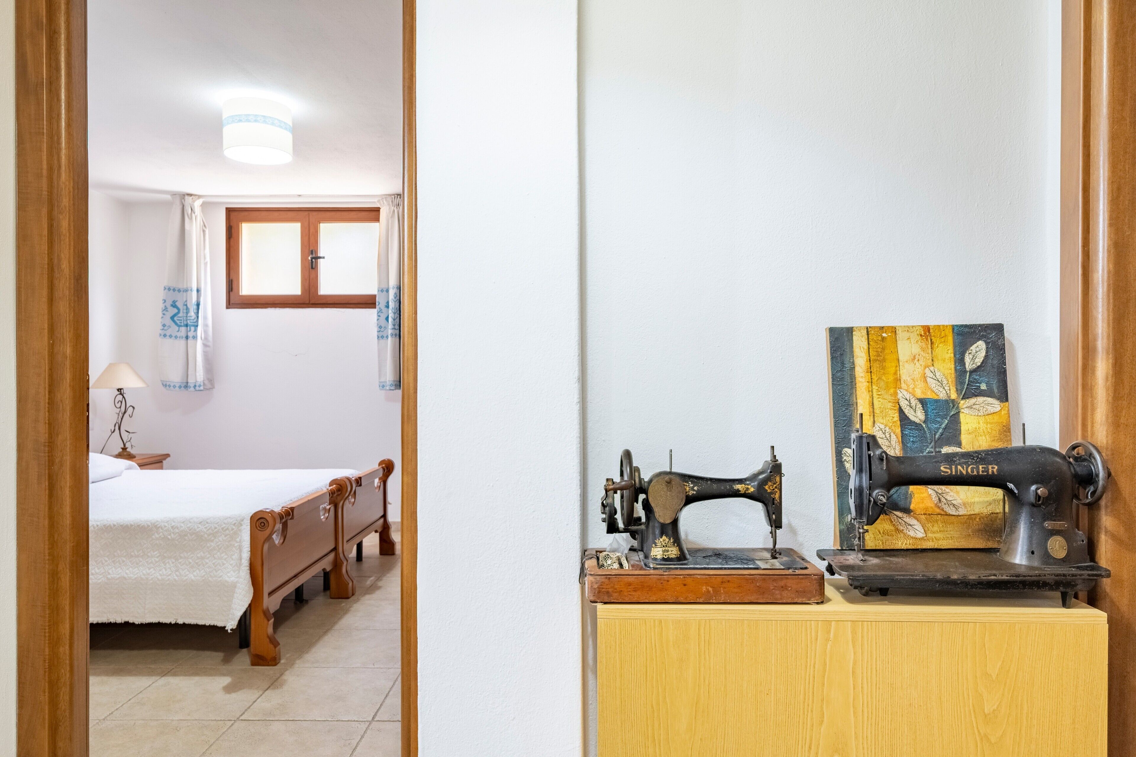Une chambre à coucher avec un lit, une armoire en bois et une machine à coudre Singer.
