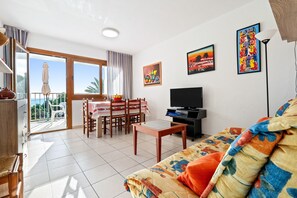A living room with a sofa, TV, dining table, and chairs.