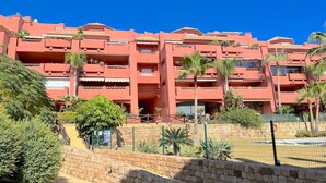 Un hôtel à plusieurs étages doté de balcons, d’un mur en pierre et de plantes tropicales.