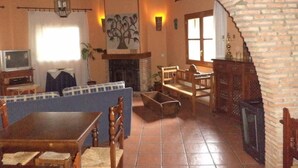 A cozy living room with a fireplace, wooden furniture, and a tiled floor.