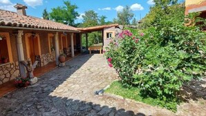 A courtyard with stone flooring, a covered seating area, and a garden with flowering plants.