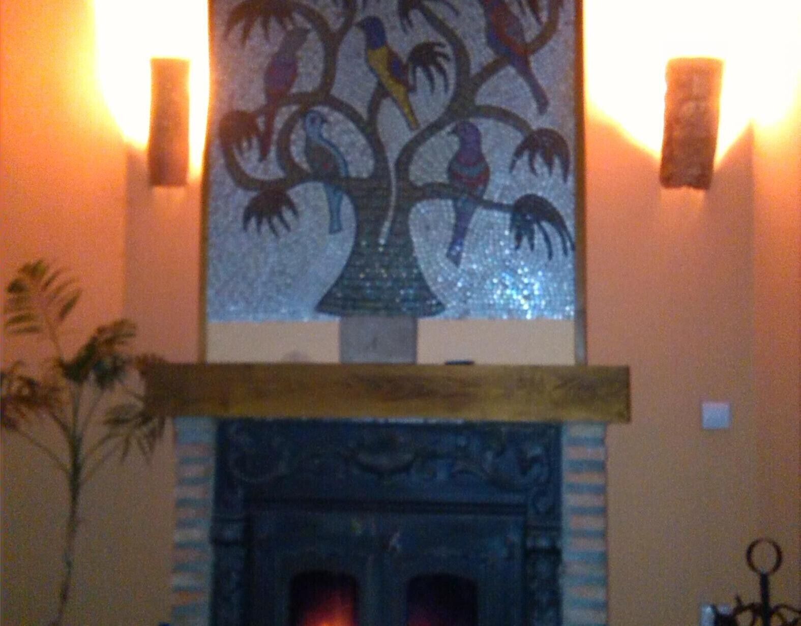 Une cheminée surmontée d’une fresque représentant un arbre décoratif.