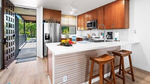 A modern kitchen with wooden cabinets, stainless steel appliances, and a large island with stools.