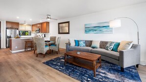 A modern living room with a grey sofa, blue and white cushions, a wooden coffee table, and a blue patterned rug.