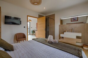Una moderna camera d'albergo con un letto, una televisione, un bagno con un lavandino e una sedia.