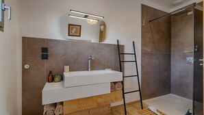 A modern bathroom with a white sink, mirror, and shower.