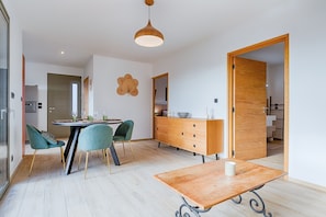 A modern kitchen with a dining area, wooden cabinets, and a unique wall decoration. - Apartment "Casa Zen" with Private Terrace, Private Garden and Wi-Fi (Vernosc-lès-Annonay)