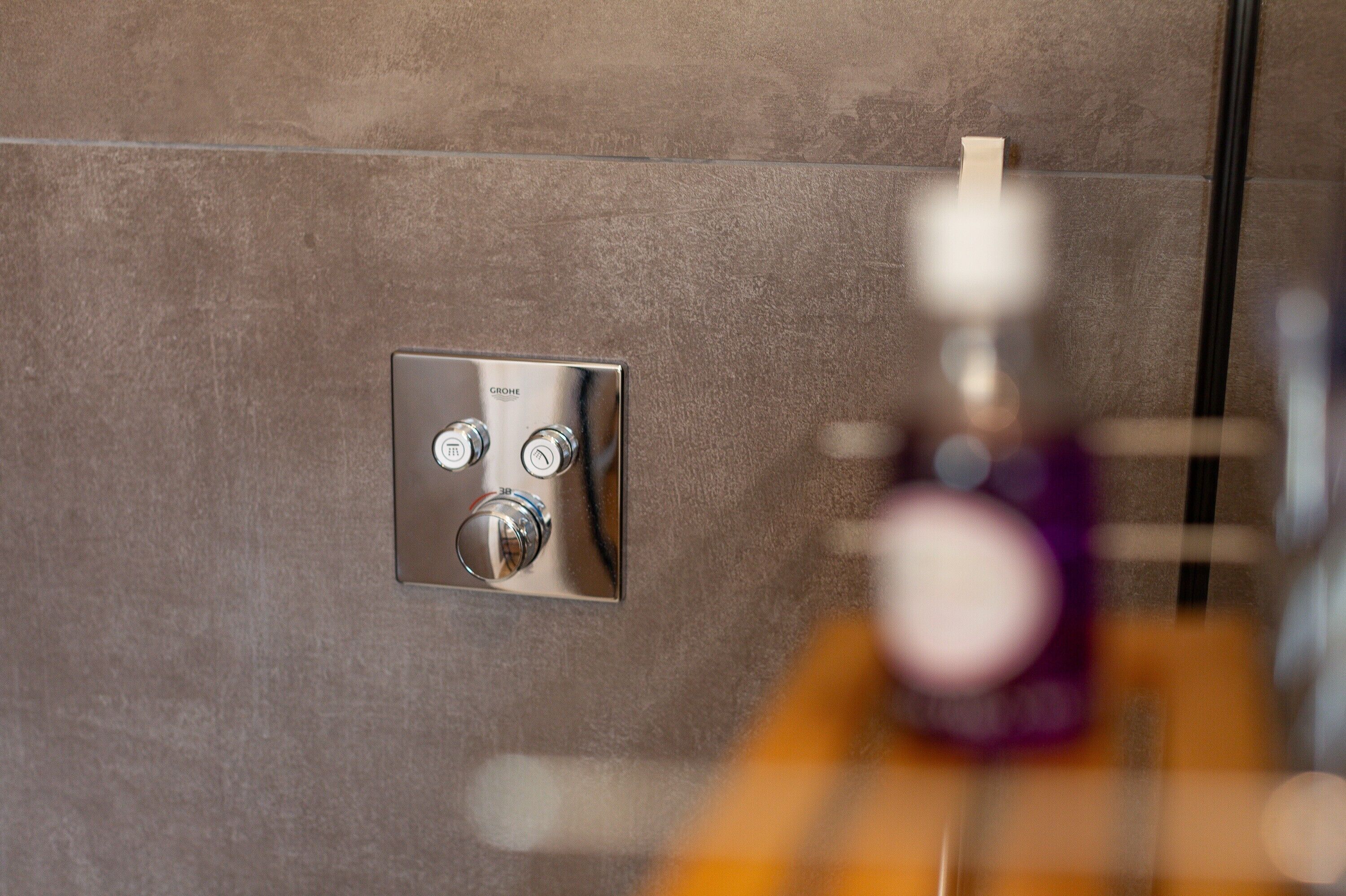 A bathroom with a modern shower control panel on a textured wall.