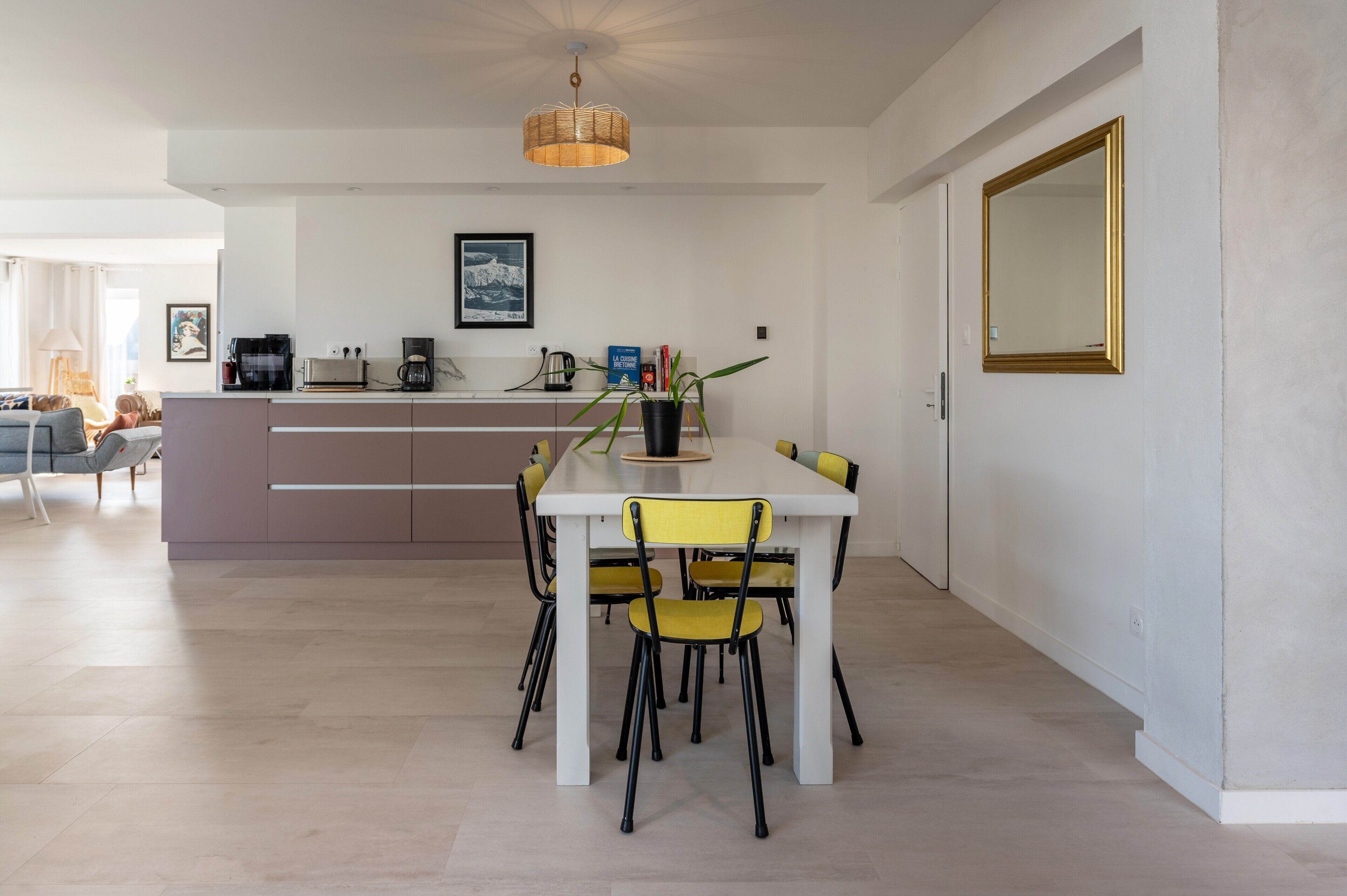 Une cuisine moderne avec un coin repas, comprenant un îlot central, des chaises et un luminaire suspendu.