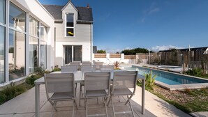 Une maison moderne dotée d’une piscine, d’un espace salon extérieur et d’une clôture en bois.